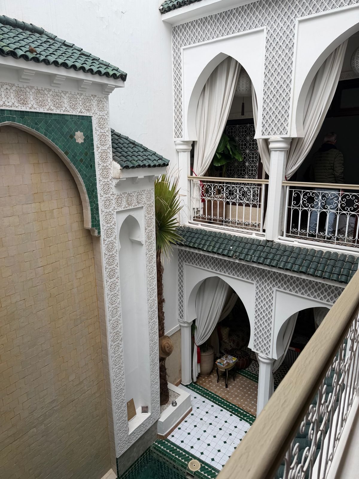 Elegant Moroccan riad interior with white and green tilework, evoking Riad Assakina's Mellah quarter setting in Marrakech